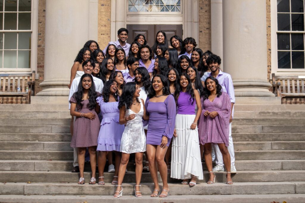 UNC Chalkaa on steps of UNC building. All wearing shades of light purple and white.