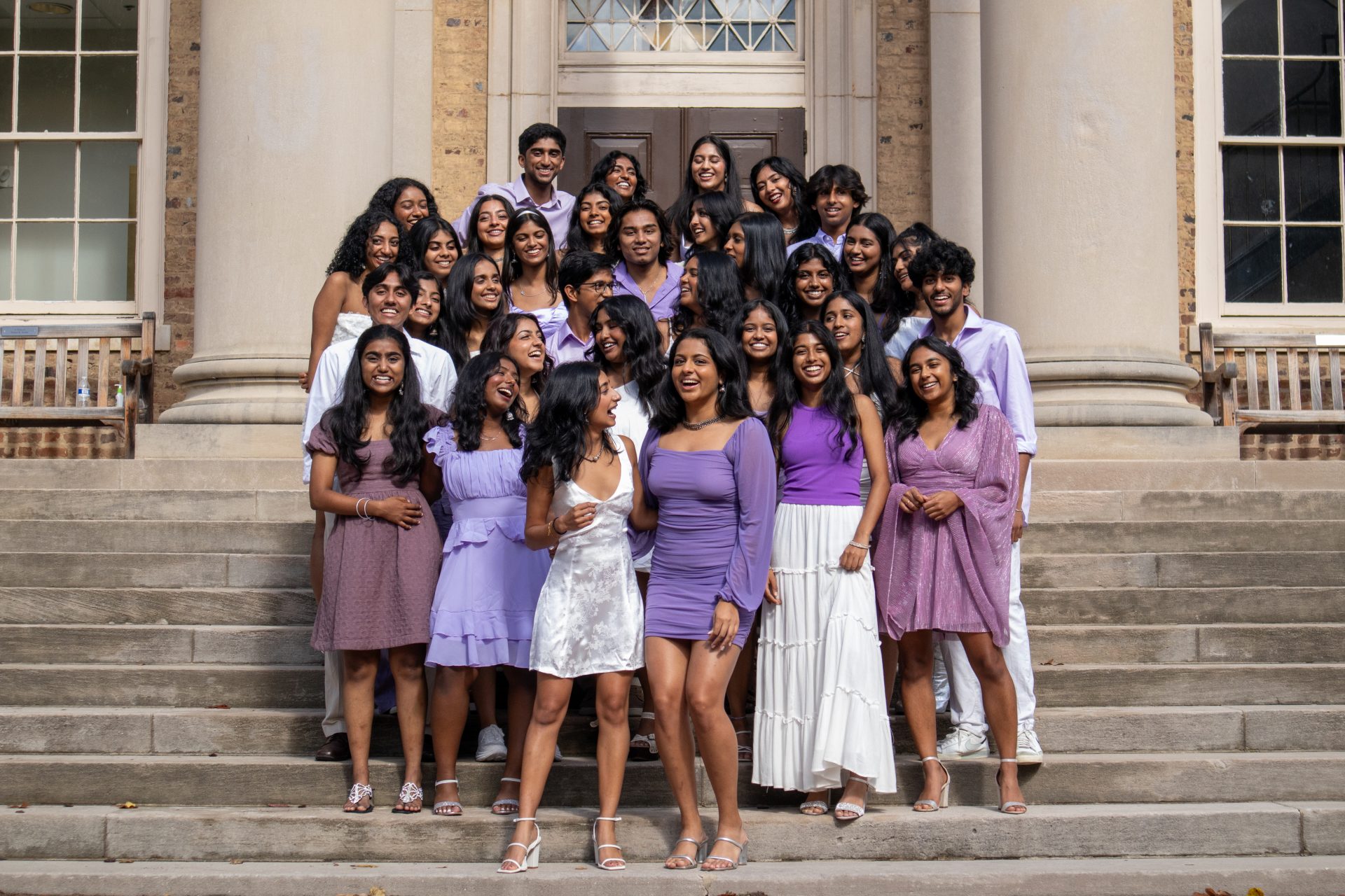 UNC Chalkaa on steps of UNC building. All wearing shades of light purple and white.